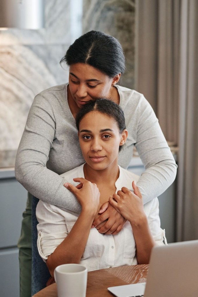 A woman placing a comforting hand on another woman's shoulder
